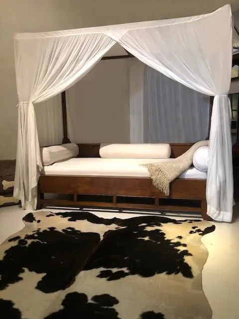 White canopy bed with cowhide rug.