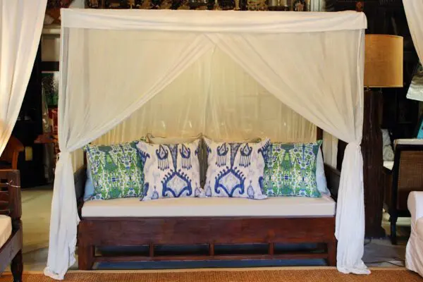 Canopied sofa with decorative pillows and drapes.