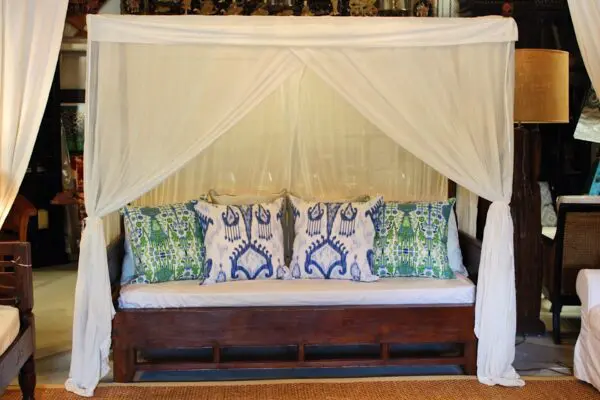 Canopied sofa with decorative cushions and drapes.