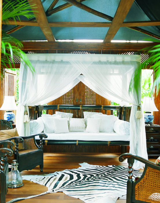 Canopy bed with zebra print rug.