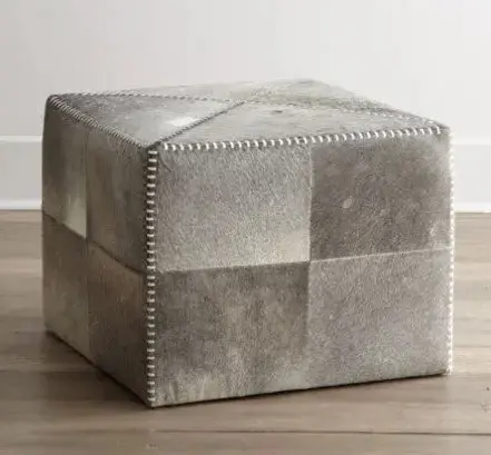 A square ottoman with grey leather and silver studs.