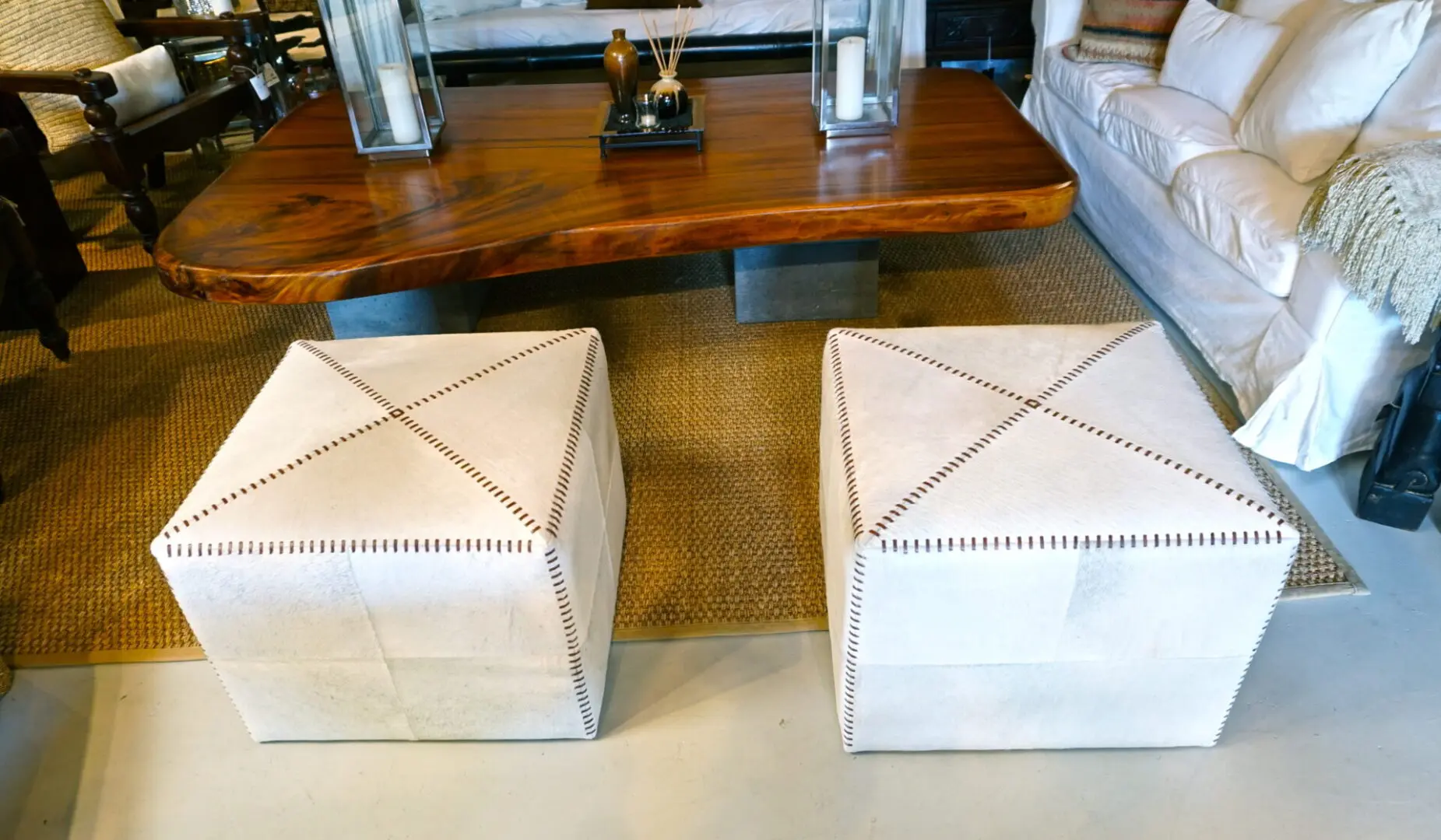 Two white ottomans with brown stitching.