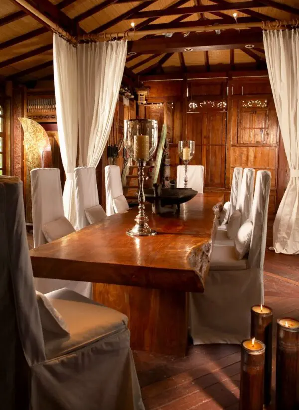 A dining room table with white chairs and curtains.