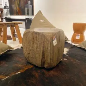 Wooden stool on a textured floor rug.