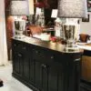 A black buffet with two lamps on top of it.
