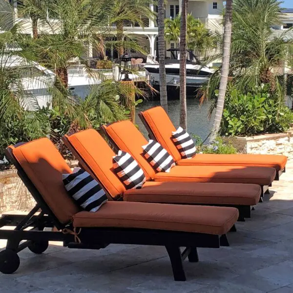 Orange loungers with striped pillows by water.