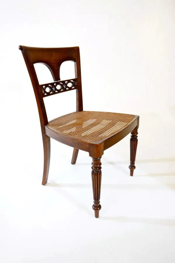 A wooden chair with a woven seat on top of it.