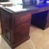 Wooden desk with multiple drawers and papers.