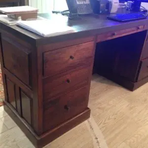 Wooden desk with multiple drawers and papers.