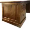 Wooden desk with drawers and vertical paneling.