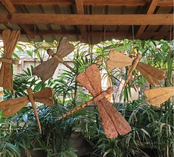 Wooden dragonfly decorations hanging in greenery.