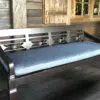 Wooden bench with blue cushion and intricate design.