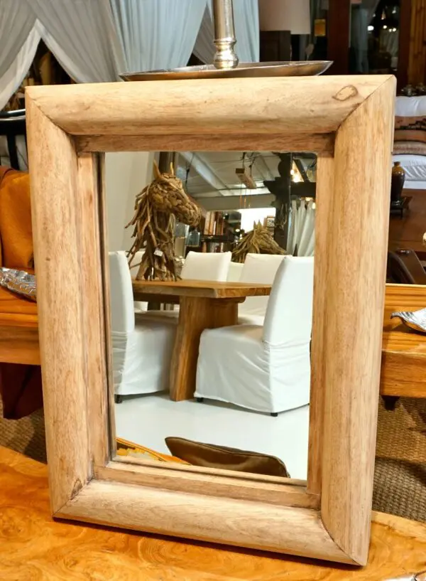 Wooden-framed mirror reflecting a dining area.