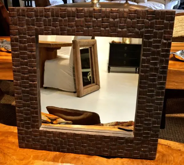 Decorative mirror with a textured frame.