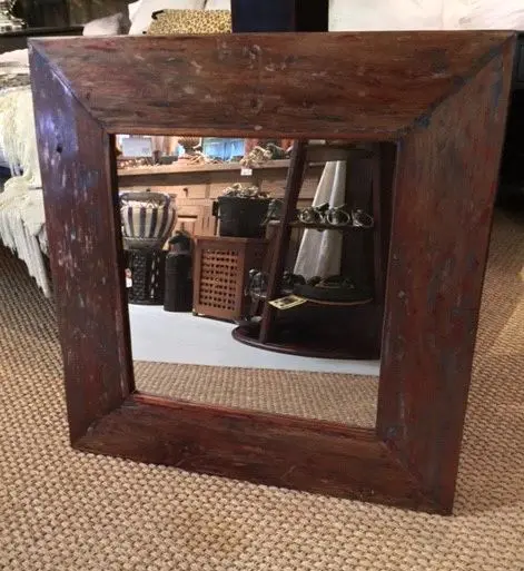 Rustic wooden mirror with detailed frame.