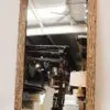 Wood-framed mirror reflecting interior space.