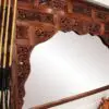 Intricately carved wooden mirror with reflection.