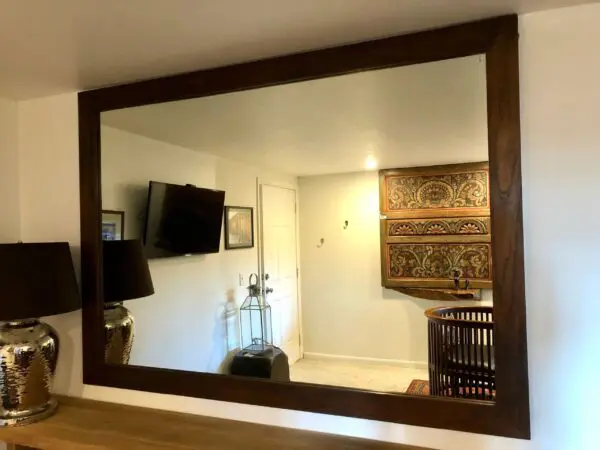 Framed mirror reflecting a decorated interior.