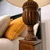 Wooden lamp next to yellow and white pillows.