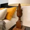 Wooden lamp beside yellow and gray pillows.