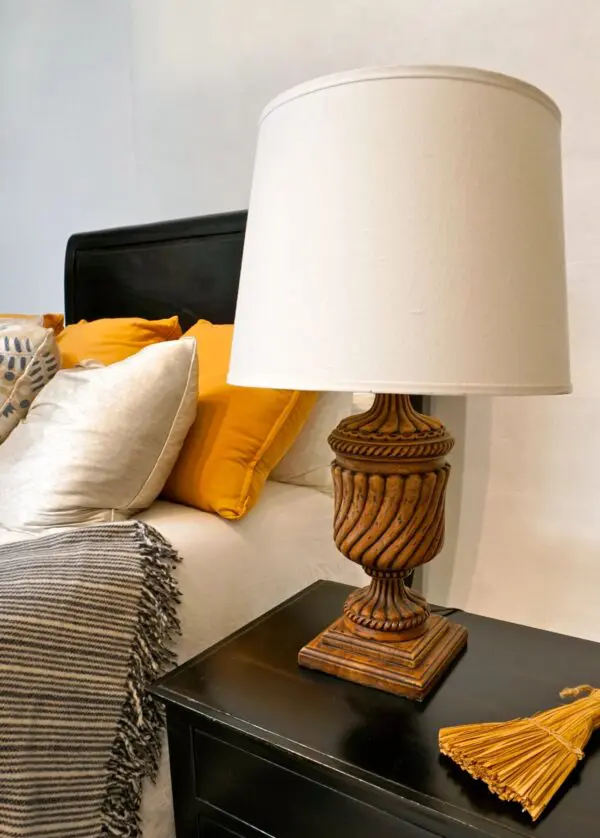 Wooden lamp on bedside table with pillows.