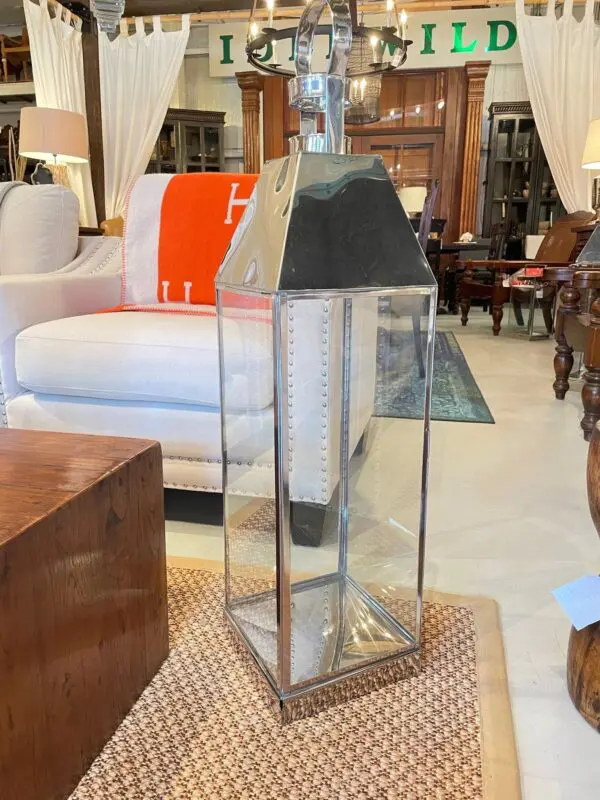 Metal and glass lantern beside a sofa.