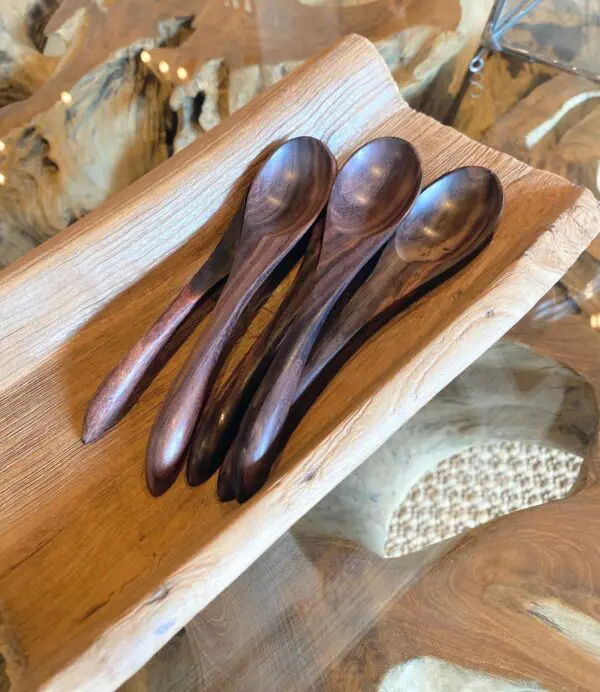 A wooden tray with three spoons on it.