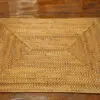 A wooden table with a woven placemat on it.