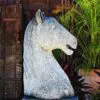 A horse statue sitting in front of some plants.