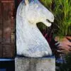 A statue of a horse 's head on top of a stone block.