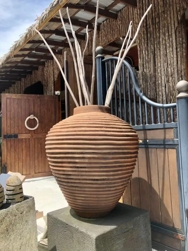 Clay vase with sticks, rustic setting.