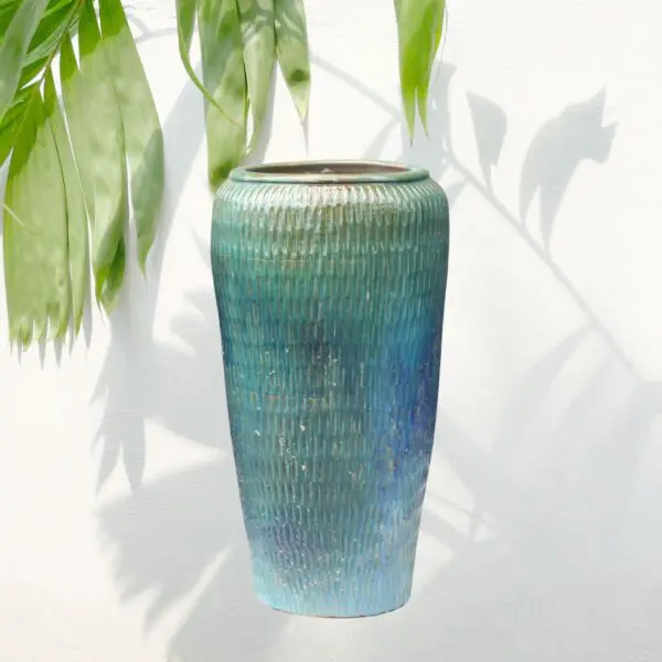 Blue textured vase with green leaves.