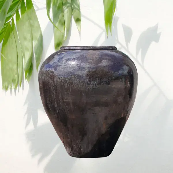 Black ceramic vase with green leaves.