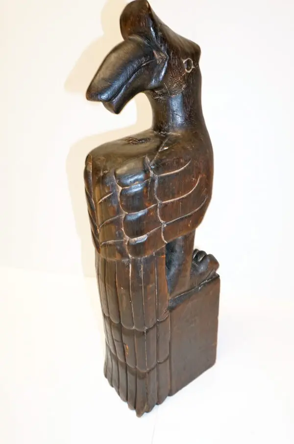 A wooden statue of an eagle on top of a block.