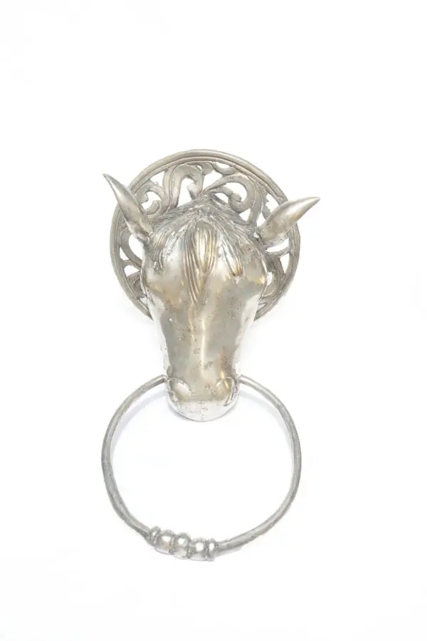 A silver horse head with a ring on the back of it.