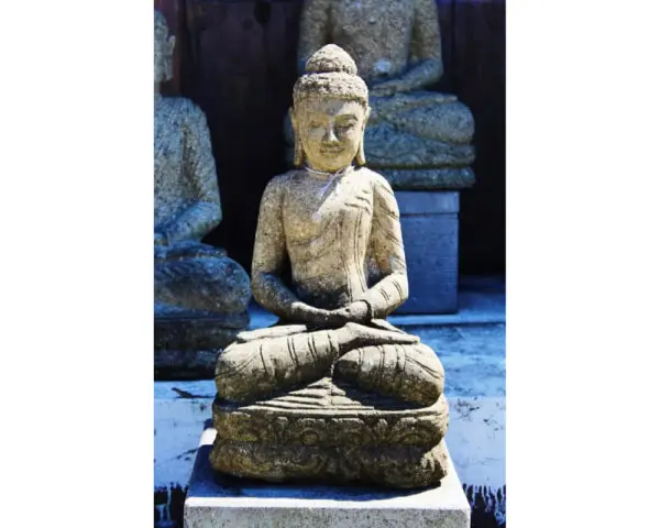 A statue of buddha sitting on top of a stone slab.