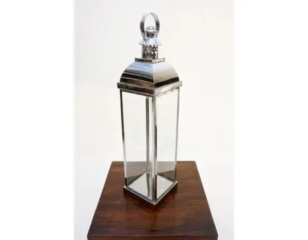 A silver lantern sitting on top of a wooden table.