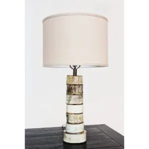 A table lamp with a white shade on top of a black table.