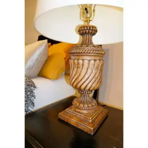 A lamp on top of a table next to a bed.