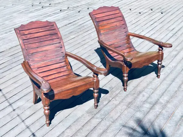 Two wooden chairs on a deck.