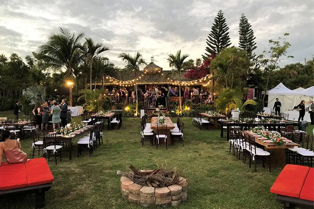 Outdoor event with tables and string lights.