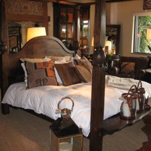 A bedroom with four poster bed and large mirror.