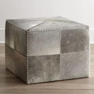 A square ottoman with grey leather and silver studs.