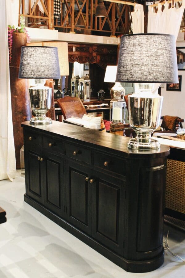 A black buffet with two lamps on top of it.