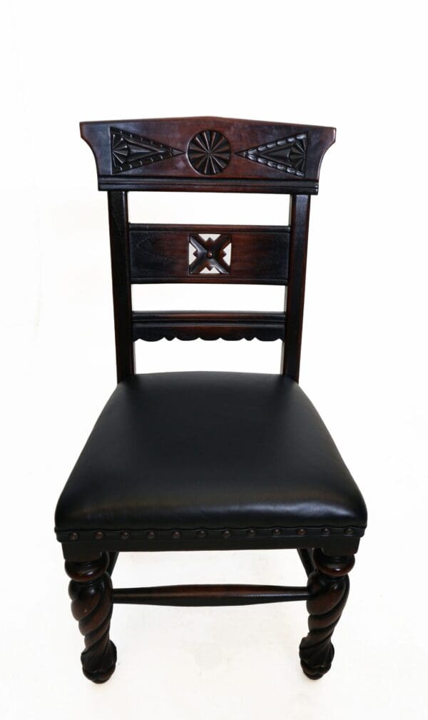 A wooden chair with black leather seat and back.