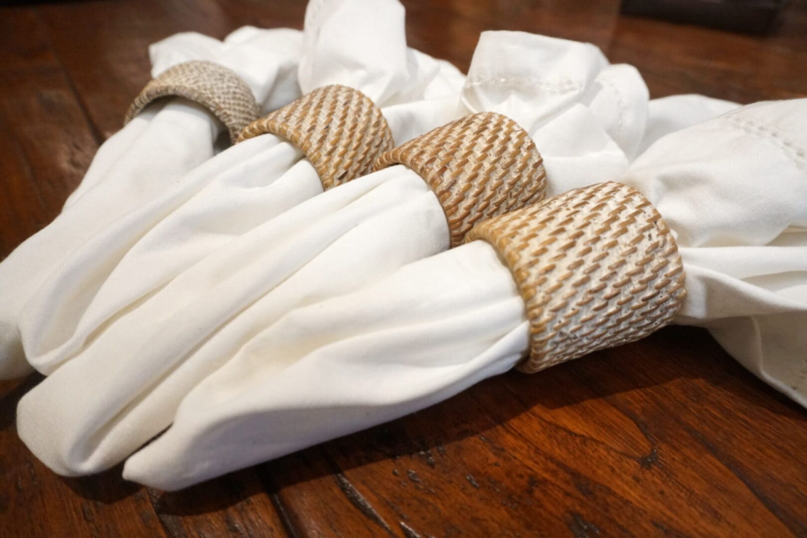 A wooden table with white napkins and rope wrapped around the ends.