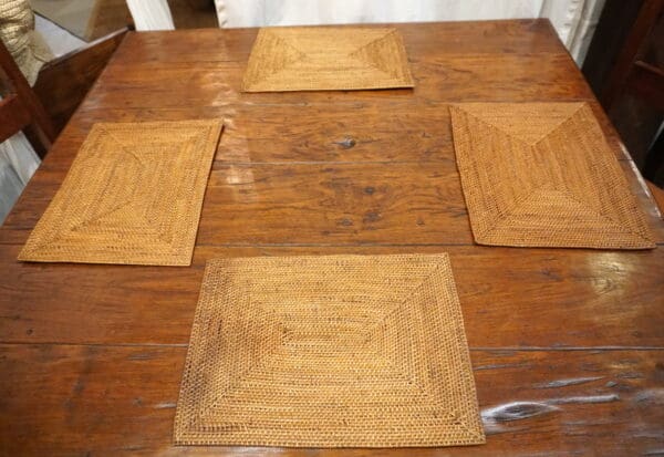 A wooden table with four square plates on it.