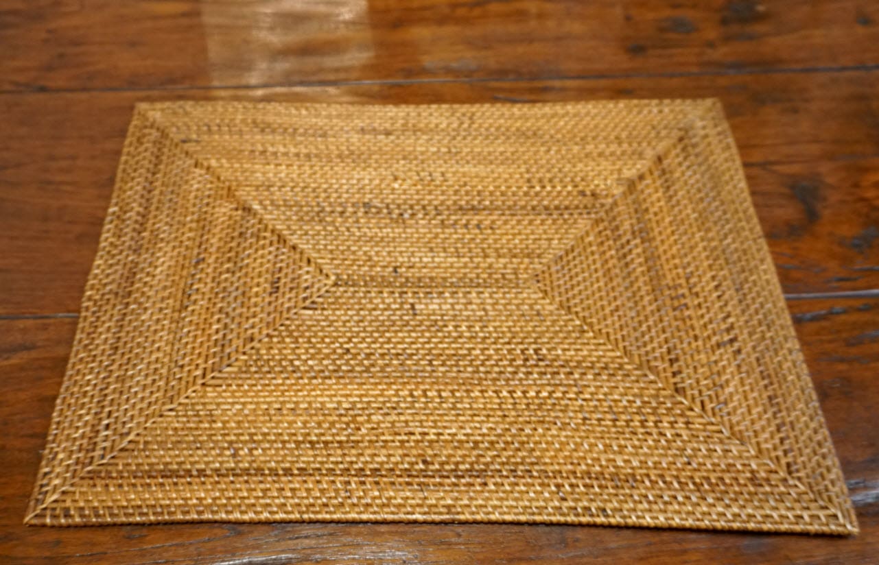 A wooden table with a woven placemat on it.