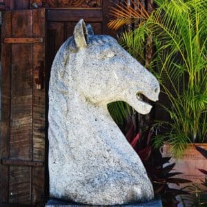A horse statue sitting in front of some plants.