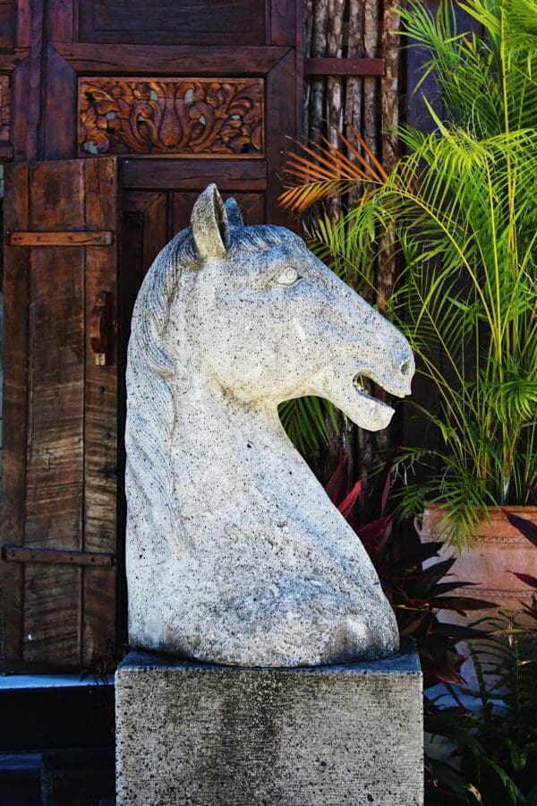 A horse statue sitting in front of some plants.